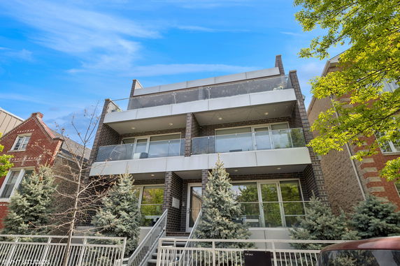 Front view of a modern multi-story building with balconies and front entrance.