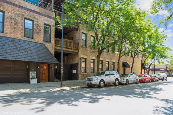 Front view of a multi-story brick building with an attached garage and balconies.