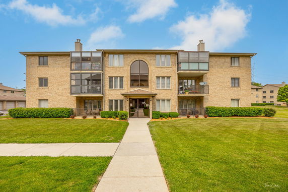 Front view of a multi-story apartment building with a central entrance and balconies.