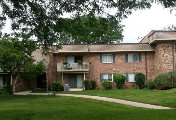 Front view of a two-story brick apartment building with a balcony.