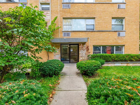 Front view of a brick apartment building with a glass entrance door.