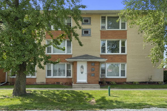 Front view of a three-story brick building with multiple windows.