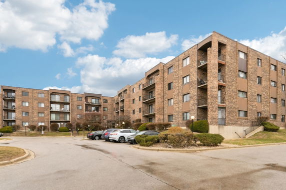 Front view of a multi-story brick apartment building with balconies.