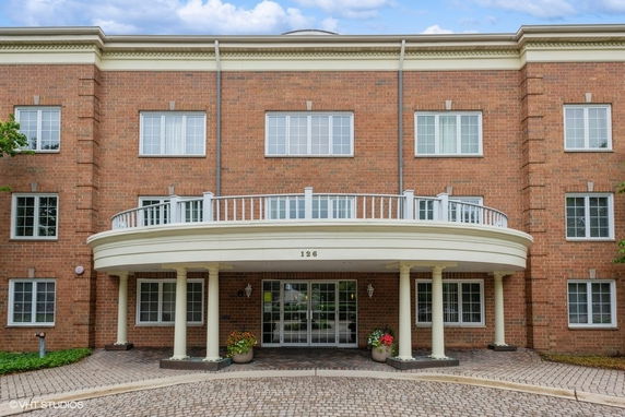 Front view of a brick building with multiple windows and a covered entrance with columns.