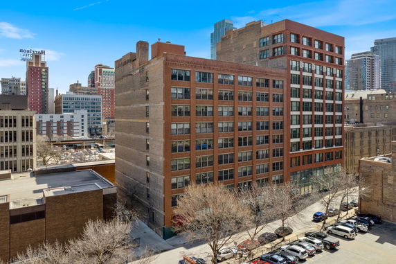 Front view of a mid-rise urban building with multiple windows and a brick facade.