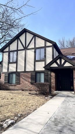 Front view of a house with tudor-style architecture and brick details.