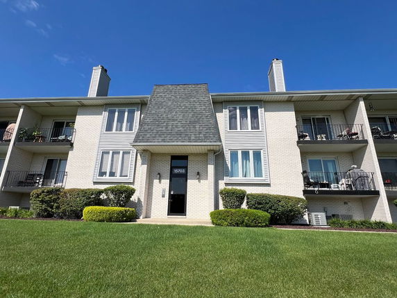 Front view of a multi-story building with balconies and chimneys.