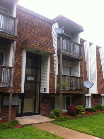 Front view of a multi-story apartment building with balconies and satellite dishes.