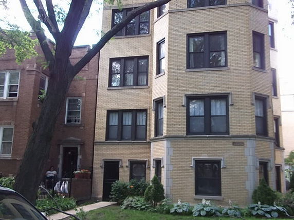 Front view of a multi-story brick building with large windows.