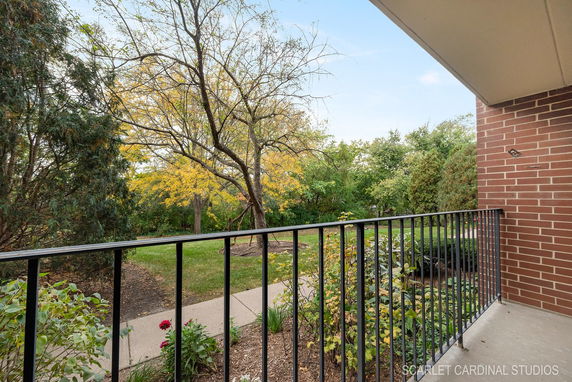 View from a balcony showing a grassy area with trees and a walkway.
