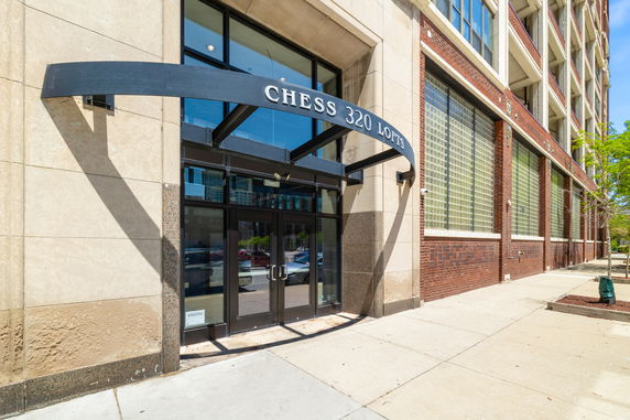 Front view of a building entrance with glass doors and an awning labeled 'Chess 320 Lofts.'