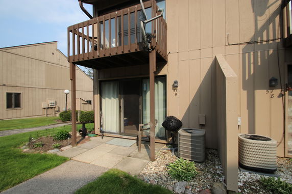Front view of a two-story building with a small balcony and sliding glass door.