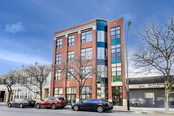 Front view of a multi-story red brick building with large windows.