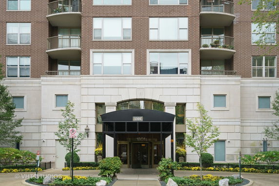 Front view of a multi-story residential building with balconies and a central entrance.