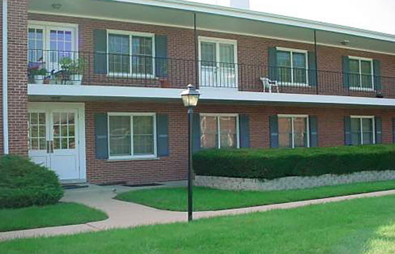 Front view of a two-story brick building with balconies and shuttered windows.
