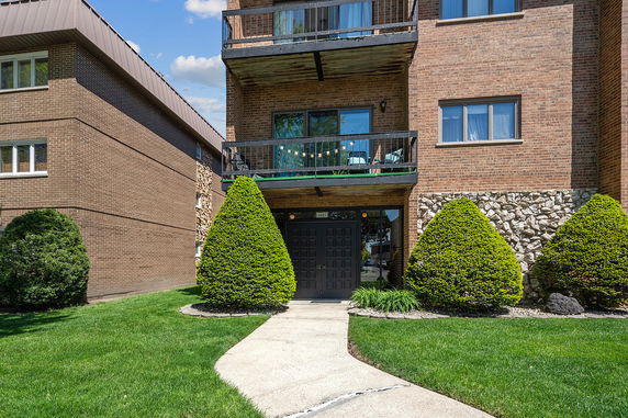 Front view of a brick apartment building with balconies and a main entrance.