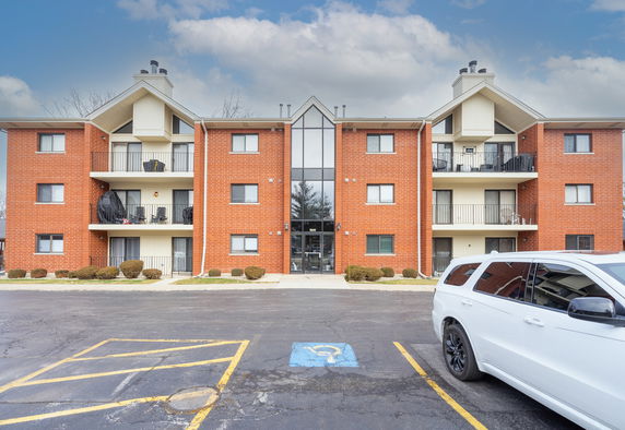 Front view of a multi-story brick apartment building with balconies.