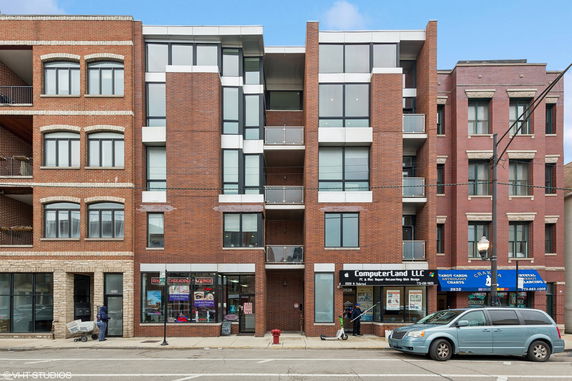 Front view of a multi-story building with brick facade and glass balconies.