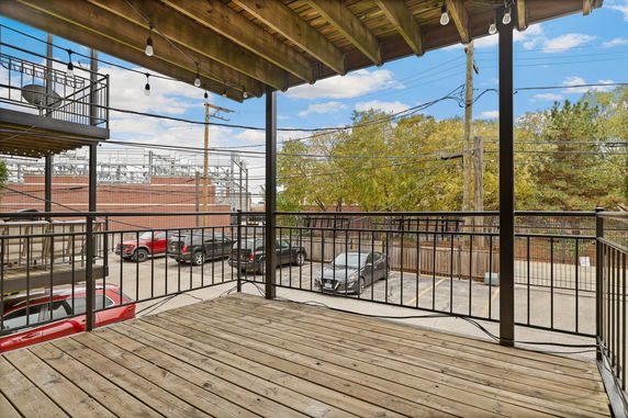 View of a parking area with multiple cars from a wooden deck.