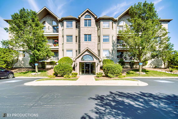 Front view of a multi-story residential building with a central entrance and balconies on each side.
