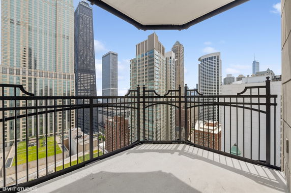 Panoramic view from a balcony overlooking skyscrapers in a cityscape.