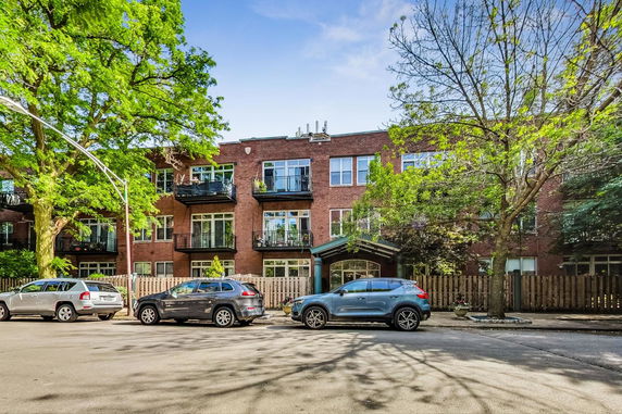 Front view of a three-story brick apartment building with balconies.