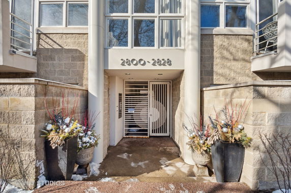 Front view of a building entrance with stone facade and decorative planters.