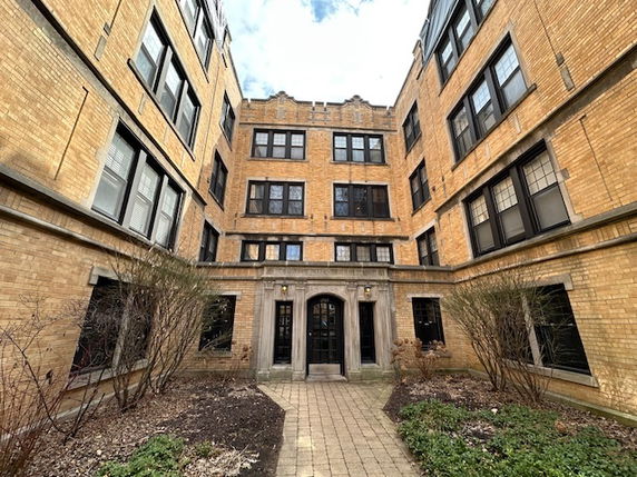 Front view of a multi-story brick apartment building with large windows.