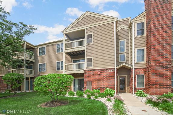 Front view of a multi-story residential building with balconies and brick exterior.