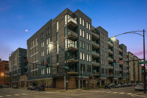 Front view of a multi-story apartment building on a city street corner.