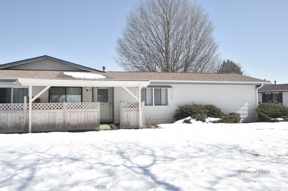Front view of a single-story house with a porch and a snow-covered yard.