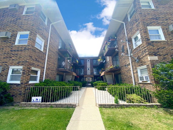 Front view of a multi-story brick apartment building with balconies.