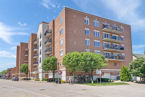 Front view of a multi-story apartment building with balconies and brick exterior.