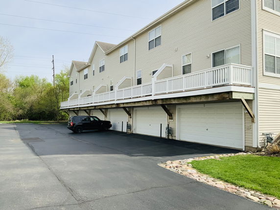 Front view of a multi-story building with garages on ground level and balconies above.