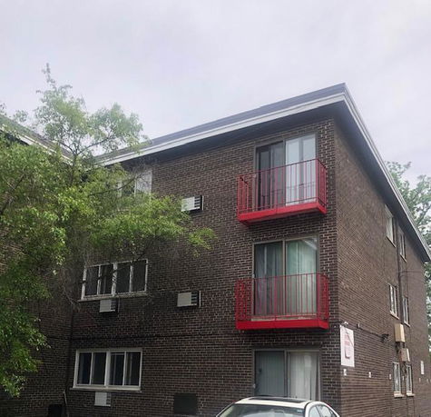 Front view of a multi-story brick building with red balconies.