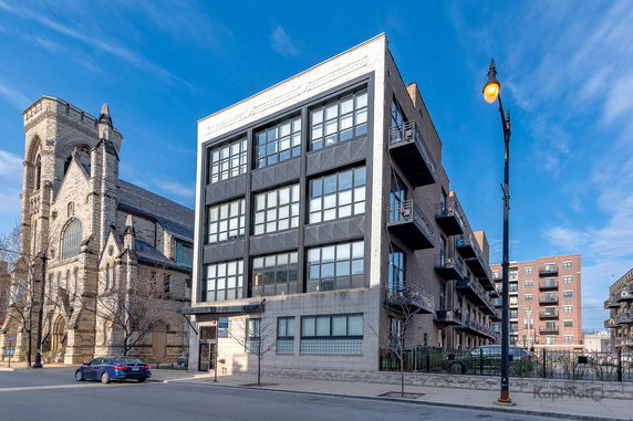Front view of a modern multi-story apartment building next to a historic stone church.