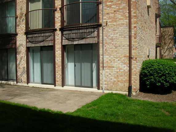 Front view of a brick multi-story building with balconies and large windows.