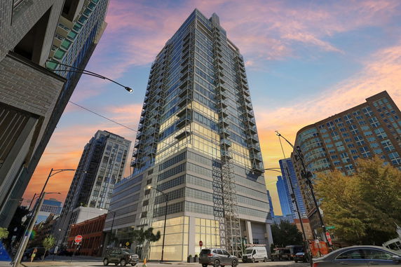 Front view of a tall glass and steel high-rise building in an urban setting.