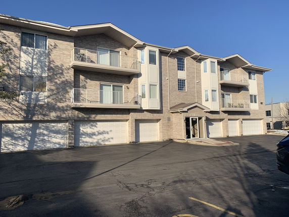 Front view of a three-story building with multiple garages at the ground level.