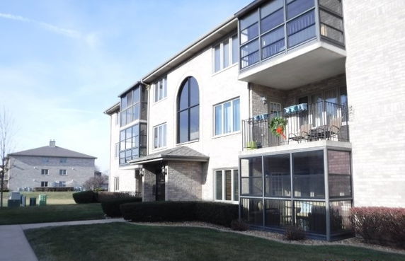 Front view of a multi-story apartment building with balconies and large windows.
