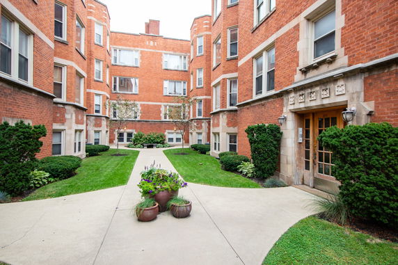 Front view of a multi-story brick apartment building with decorative entrance.