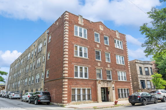 Front view of a multi-story brick building with decorative stonework and multiple windows.