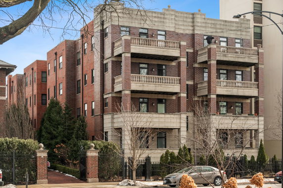 Front view of a multi-story brick apartment building with balconies.