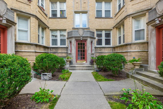 Front view of a multi-story brick building with a central entrance and several windows.