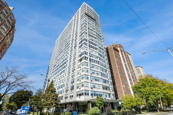 Front view of a tall residential building with multiple floors and large windows.