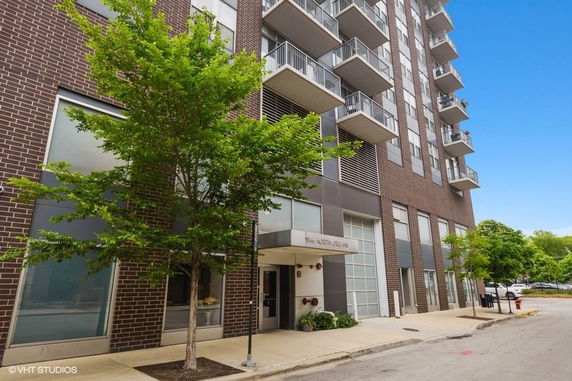 Front view of a multi-story building with balconies and a brown brick facade.