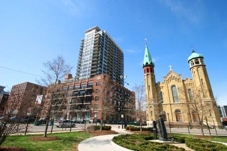 Front view of a tall apartment building next to a historic church with towers.