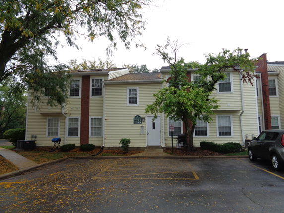 Front view of a two-story residential building with siding and brick accents.