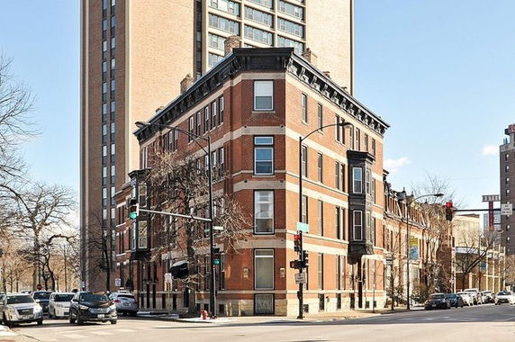 Front view of a multi-story brick building on a street corner.