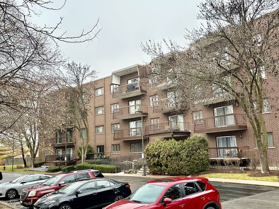 Front view of a multi-story brick apartment building with balconies.